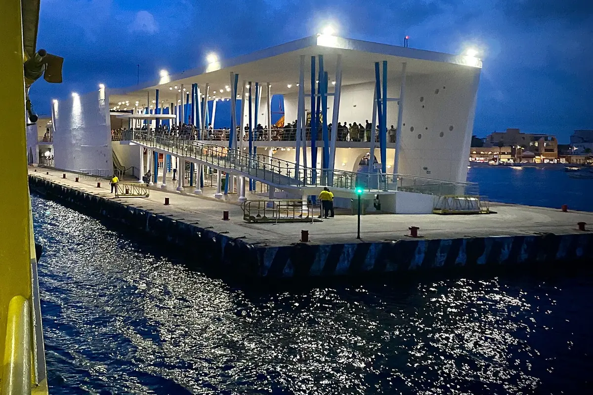 Osvětlený bílý terminál osobních trajektů na vodě za soumraku v San Miguel de Cozumel