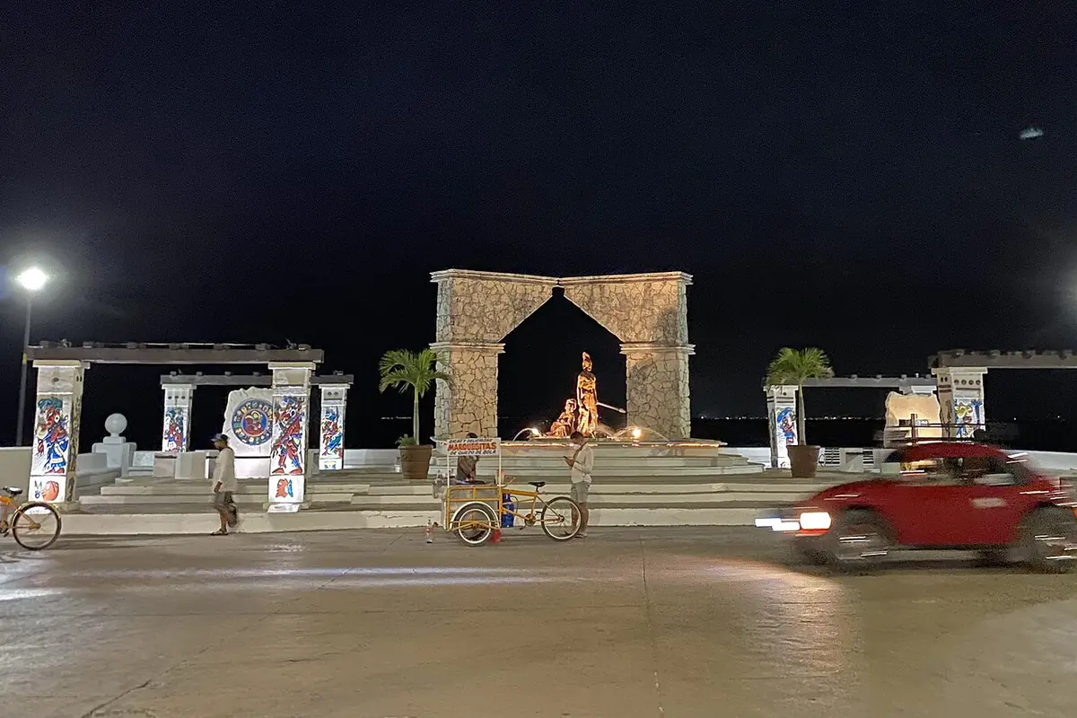 Malecón v San Miguel de Cozumel v noci, v pozadí osvětlený kamenný oblouk